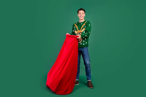 Foto von interessierten Kerl öffnen Big Bag wow Reaktion tragen Hirsch Ornament Pullover isoliert grüne Farbe Hintergrund — Stockfoto