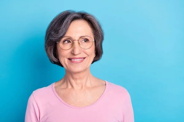 Foto av modent smilende positiv drømmekvinne i briller ser ut som et copyspace som drømmer isolert på blå bakgrunn – stockfoto