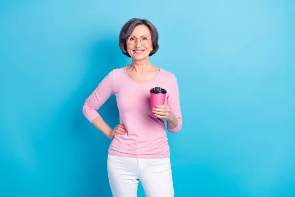 Fénykép boldog mosolygós vidám bájos érett nő szemüvegben ivás kávé elszigetelt kék színű háttér — Stock Fotó