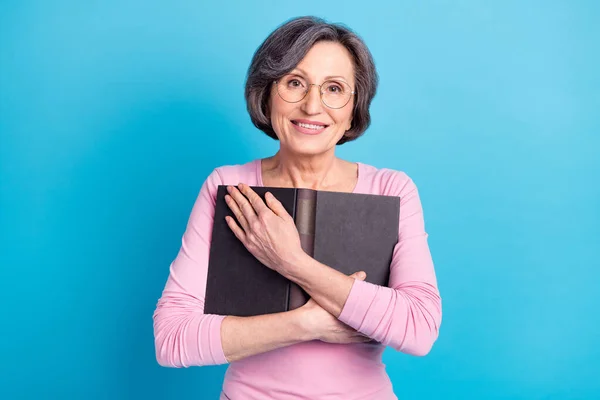 Φωτογραφία του ευτυχισμένη θετική γοητευτικό ονειρική ώριμη γυναίκα σε γυαλιά αγκαλιάσει το βιβλίο απομονωμένο σε μπλε φόντο χρώμα — Φωτογραφία Αρχείου