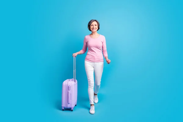 Pełny rozmiar zdjęcie szczęśliwy pozytywny nastrój dziewczyna iść pieszo z bagażem pozostawiając na wakacje odizolowane na tle niebieskiego koloru — Zdjęcie stockowe