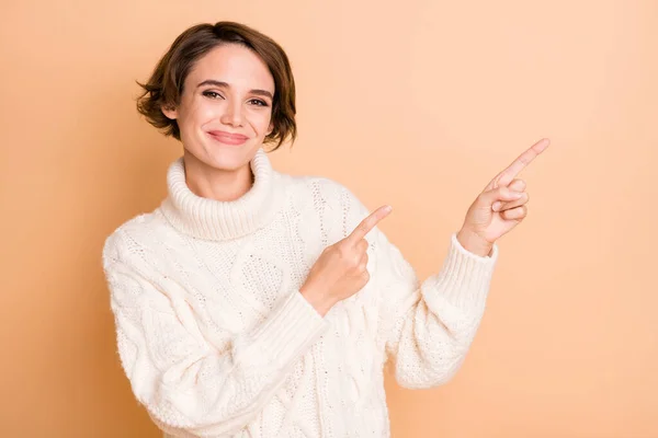 Fénykép portré női diák pulóver mutató ujjak üres tér ajánló elszigetelt pasztell bézs színű háttér — Stock Fotó