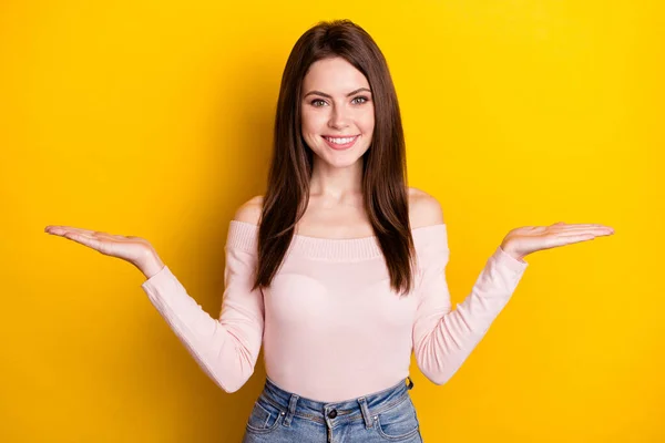 Foto av ung vacker leende flicka hålla händerna i balans reklam produkt erbjudande isolerad på gul färg bakgrund — Stockfoto