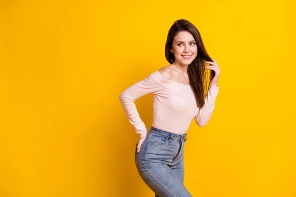 Foto de doce adorável jovem mulher vestida off-ombros suéter sorrindo olhando para trás espaço vazio isolado cor amarela fundo — Fotografia de Stock