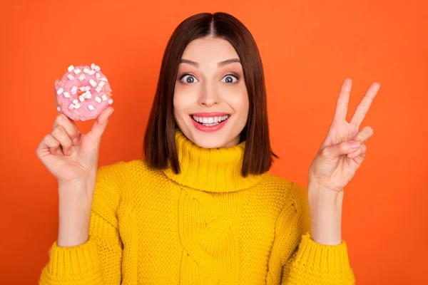 Foto da jovem feliz sorriso positivo mostrar paz fresco v-sign biscoitos doce isolado sobre cor laranja fundo — Fotografia de Stock