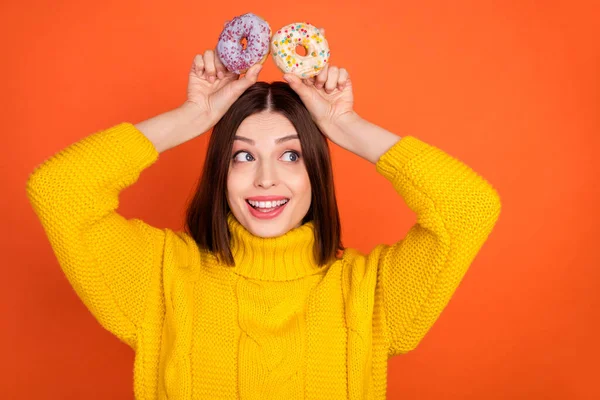 Photo de jeune femme excitée heureux sourire positif cookies oreilles regard ludique espace vide isolé sur fond de couleur orange — Photo