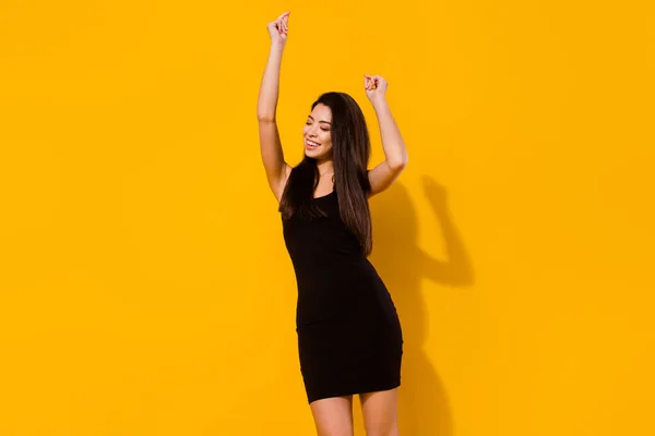 Φωτογραφία από δροσερό μελαχρινή hairdo νεαρή κοπέλα χορό φορούν μαύρο φόρεμα απομονωμένο σε ζωντανό κίτρινο χρώμα φόντο — Φωτογραφία Αρχείου