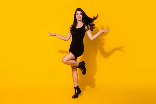 Fotografie de dimensiune completă a părului impresionat brunetă tânără doamnă dans purta pantofi rochie neagră izolat pe fundal de culoare galbenă — Fotografie, imagine de stoc