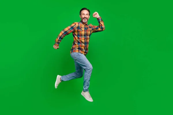 Full length body size view of attractive sporty lucky cheerful man jumping running isolated over bright green color background — Stock Photo, Image