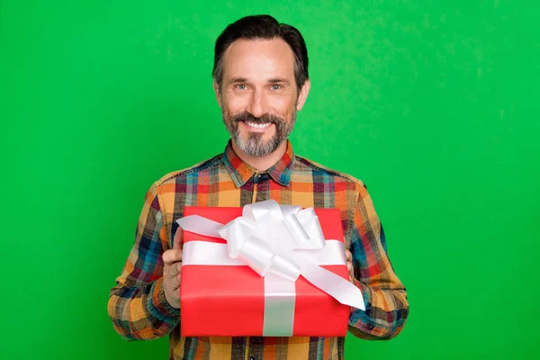Портрет привлекательного веселого человека, держащего в руках подарок, дающий вам изолированный на ярко-зеленом фоне — стоковое фото