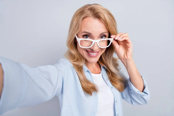 Foto di matura bella bella femmina in occhiali prendere selfie registrazione vlogging isolato su sfondo di colore grigio — Foto Stock