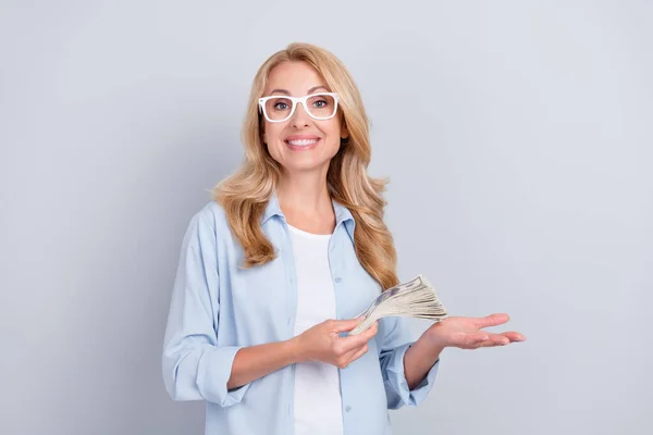 Foto di positivo banchiere signora tenere mucchio banconote in contanti indossare occhiali blu camicia isolato colore grigio sfondo — Foto Stock