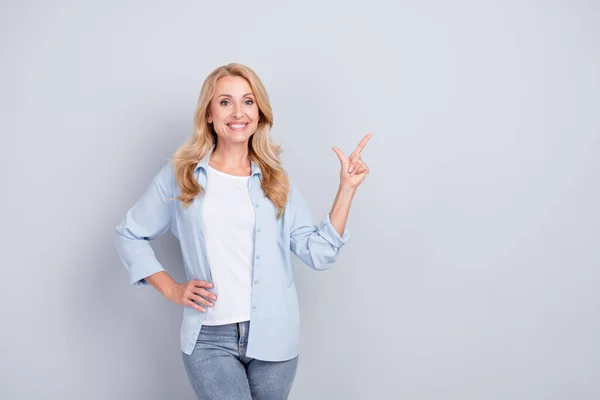 Foto av leende glad mogen kvinna peka finger copyspace reklam produkt isolerad på grå färg bakgrund — Stockfoto