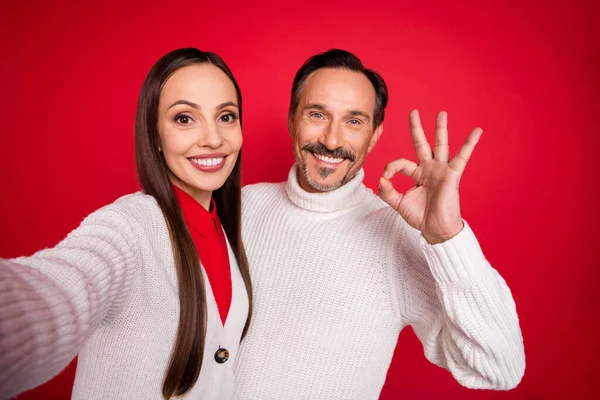 Foto do marido feliz maduro esposa elegante na moda casados pessoas fazem selfie ok sinal isolado no fundo de cor vermelha — Fotografia de Stock