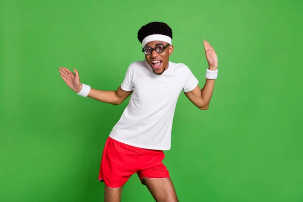 Portret van aantrekkelijke vrolijke zorgeloze jongen nerd sportman dansen plezier geïsoleerd over helder groene kleur achtergrond — Stockfoto