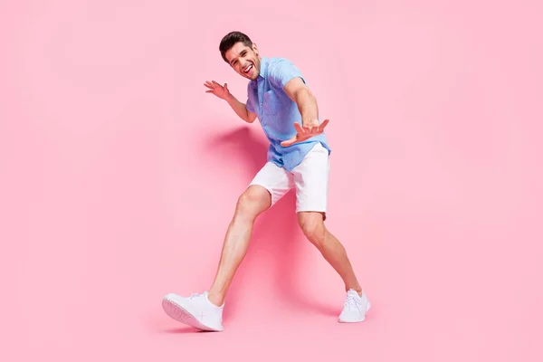 쾌활 한 긍정적 인 남자가 걷고 있는 사진 핑크 색 배경에 고립된 파란 셔츠 운동화를 신고 있습니다. — 스톡 사진