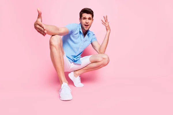 Pełna długość ciała rozmiar zdjęcie uśmiechnięty człowiek w niebieskiej koszuli siedzi taniec gestykulujące ręce odizolowane pastelowy różowy kolor tło — Zdjęcie stockowe