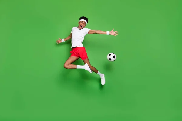 Полная длина фото впечатляет милый темная кожа мужчина носить белые футболки прыжки высокой потери мяч изолированный зеленый цвет фона — стоковое фото