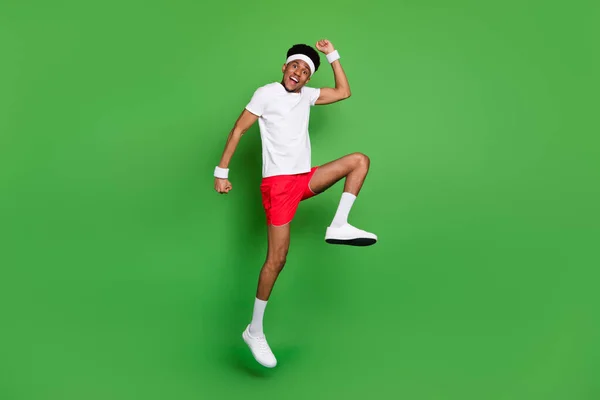 전체 몸길이의 전망 매력적 인 명랑 한 남자 운동 선수 점프밝은 녹색 배경에서 고립즐거운 즐거움을 즐기고 있다 — 스톡 사진