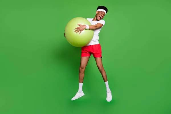 Tamanho do corpo de comprimento total vista da moda atraente desportista alegre pulando segurando fitball isolado sobre fundo de cor verde brilhante — Fotografia de Stock