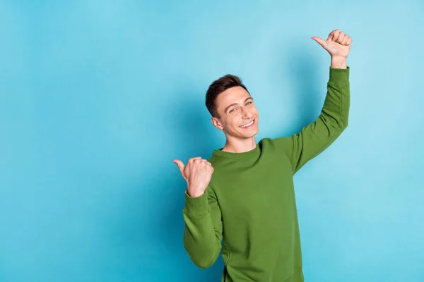 Fénykép megbízható fickó közvetlen hüvelykujj ujjak üres hely viselni zöld pulóver elszigetelt kék szín háttér — Stock Fotó