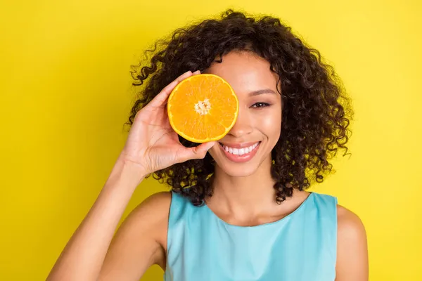 Foto de muito jovem feliz afro americana segurar laranja capa olho sorriso isolado no fundo de cor amarela — Fotografia de Stock