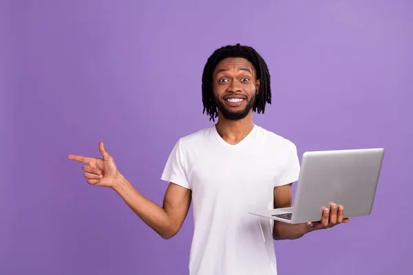 Photo de jeunes dreadlocks brun peau foncée étonné point homme espace vide tenir ordinateur portable isolé sur fond de couleur violette — Photo