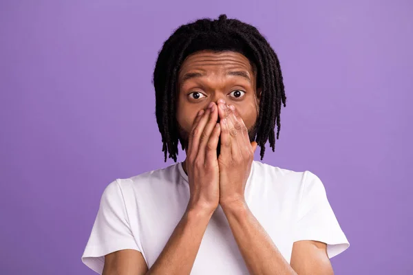 Фото напуганного афро-американского шокированного молодого человека, прикрывающего рот на руках, выделенное на фиолетовом фоне — стоковое фото