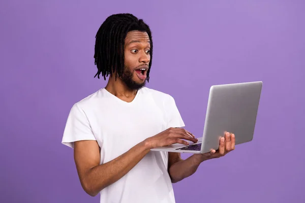 Portrait of attractive amazed cheerful guy typing using laptop isolated over bright violet purple color background — Stock Photo, Image