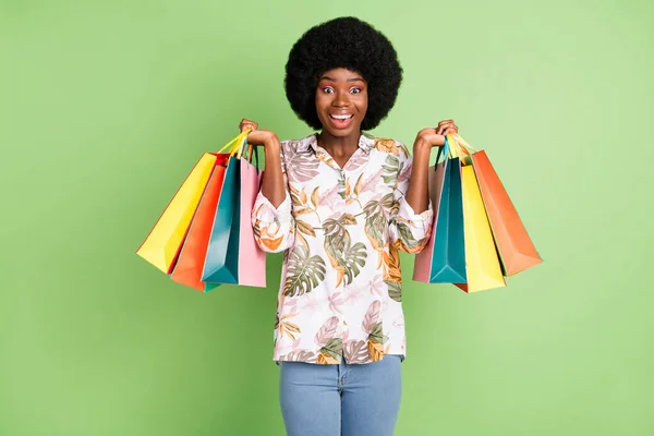 Genç heyecanlı afro kızın fotoğrafı mutlu bir gülümseme alışveriş kolik satın alma yeşil renkli arka planda izole edilmiş — Stok fotoğraf