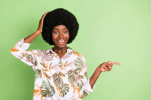 Foto da jovem menina afro surpreso sorriso feliz indicar dedo espaço vazio escolher venda promo isolado sobre fundo de cor verde — Fotografia de Stock