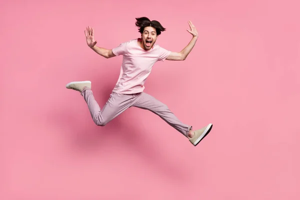 체구가 온전 한 남자가 평상복을 입고 혼자 서 파스텔 핑크 색 배경을 보고 웃으며 뛰어 오른다 — 스톡 사진