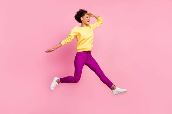 Photo of excited attractive lady wear yellow pullover jumping high looking far away empty space isolated pink color background — Stock Photo, Image