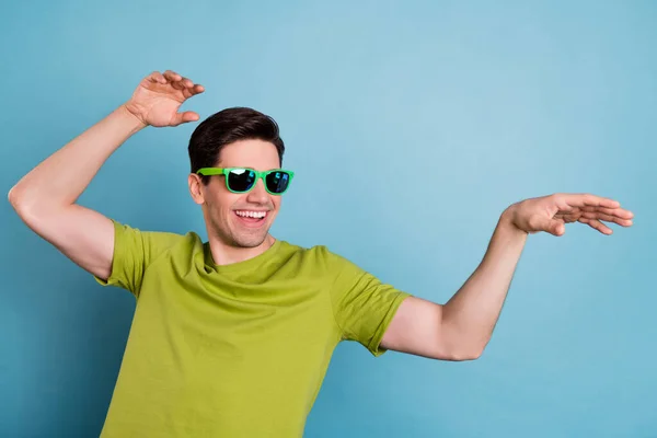 Foto de jovem muito funky usar t-shirt verde óculos escuros sorrindo dançando espaço vazio isolado fundo cor azul — Fotografia de Stock