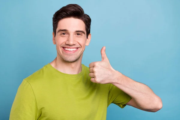 Porträtt av attraktiv glad brunhårig kille som visar tummen annons isolerad över ljusblå färg bakgrund — Stockfoto