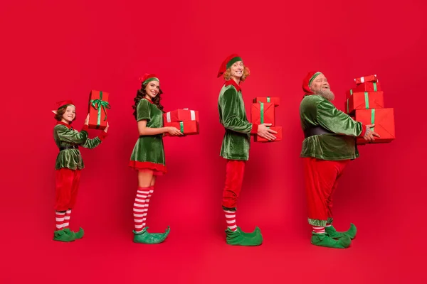 stock image Full size profile photo of queue santa service people different body type hold giftboxes wear holiday costumes isolated on red background