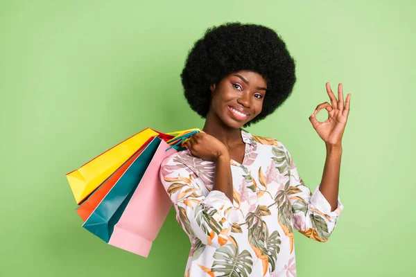 Genç afro kızın fotoğrafı mutlu pozitif gülücük torbalarını göster peki yeşil arkaplanda izole edilmiş bir tabela tavsiye et — Stok fotoğraf