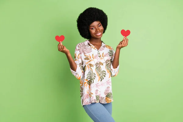 Фото молодої афро-дівчини щаслива позитивна посмішка тримає маленькі паперові серцеві почуття романтично ізольовані на фоні зеленого кольору — стокове фото