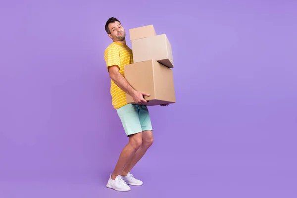 Longitud completa cuerpo tamaño foto hombre mantener cajas pesadas entrega aislado pastel violeta color fondo — Foto de Stock