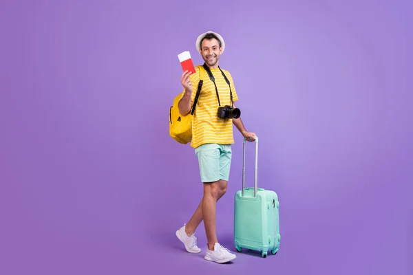 Foto lateral de perfil de tamaño completo del joven feliz sonrisa positiva viaje al extranjero boletos bolsa aislado sobre fondo de color violeta — Foto de Stock