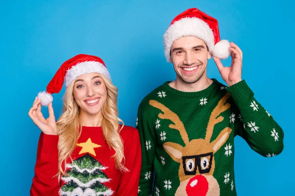 Foto retrato divertida pareja con traje de Navidad con sombreros suéter feo aislado vibrante fondo de color azul —  Fotos de Stock