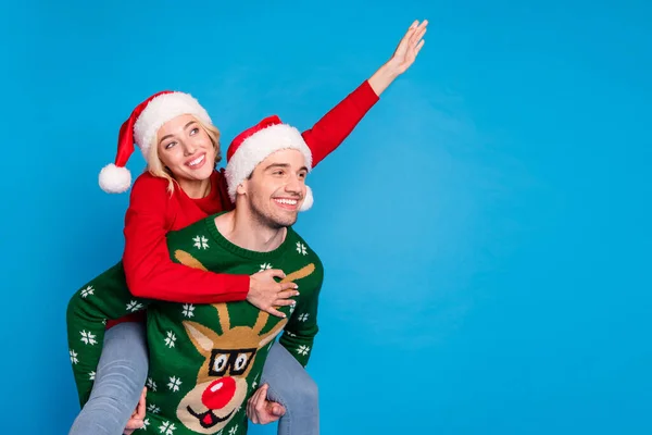 Foto retrato engraçado casal vestindo xmas roupa acenando as mãos olhando copyspace piggyback isolado vibrante azul cor fundo — Fotografia de Stock