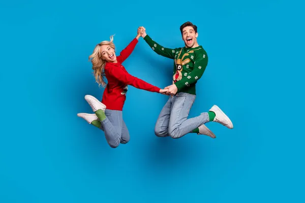 Full size profile photo of funny millennial couple jump tragen pullover jeans socken schuhe isoliert auf blauem hintergrund — Stockfoto