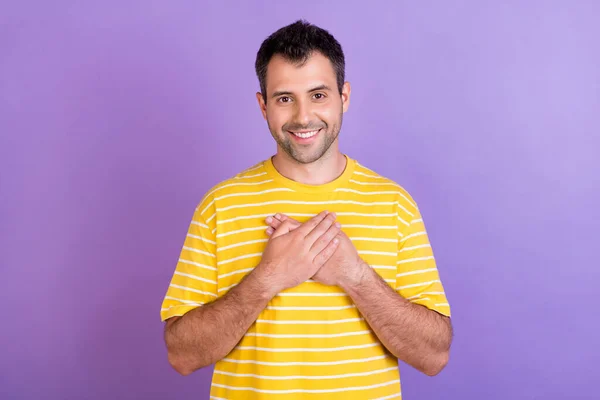 Foto di affascinante giovane onesto felice uomo allegro tenere le mani petto cuore sorriso isolato su sfondo di colore viola — Foto Stock
