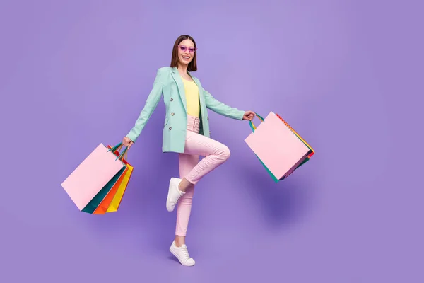 Full length portret van vrolijke tevreden dame handen houden winkel winkelcentrum pakketten geïsoleerd op violette kleur achtergrond — Stockfoto