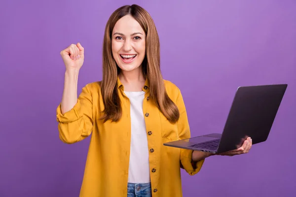 Photo of excited business woman radować zwycięstwo szczęście pięści ręka używać laptop żółty koszula izolowane nad fioletowym tle kolor — Zdjęcie stockowe