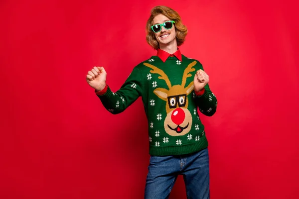 Foto de un joven dulce y brillante con gafas de suéter verde sonriendo bailando aislado fondo de color rojo — Foto de Stock
