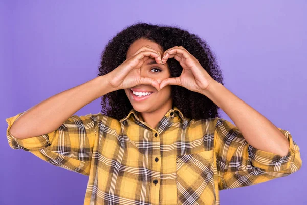 Photo of charming positive afro amerykańska kobieta pokazać palce kształt serca oko wygląd izolowany na fioletowym tle koloru — Zdjęcie stockowe