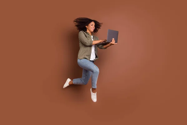 Full body profile portrait of cheerful carefree lady hold use netbook have good mood isolated on brown color background