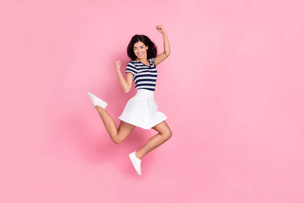 Foto de perfil de cuerpo completo de la señora del millennial joven fresco salto usar camiseta a rayas falda aislada sobre fondo de color rosa pastel —  Fotos de Stock